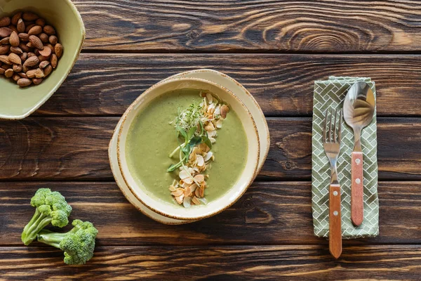 Draufsicht auf arrangierte vegetarische Sahnesuppe, Besteck und Zutaten auf Holzoberfläche — Stockfoto