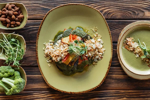 Flache Lage mit Anordnung von vegetarischem Salat, Sahnesuppe und Zutaten rundherum auf hölzerner Oberfläche — Stockfoto