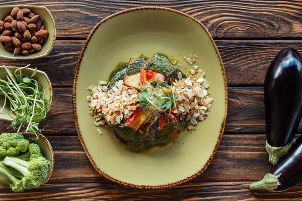 Vista dall'alto dell'insalata vegetariana con mandorle grattugiate servite sul piatto e ingredienti freschi disposti su un tavolo di legno — Foto stock