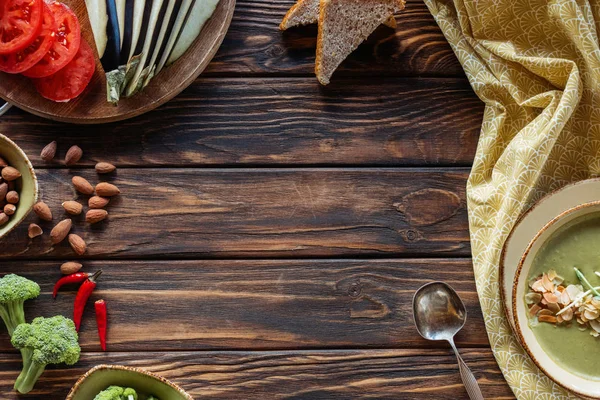 Плоский уголок с приготовленными свежими овощами и вегетарианским сливочным супом с капустой и миндалем на деревянной столешнице — стоковое фото