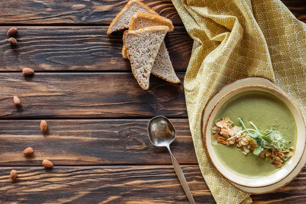 Ansicht von oben nach Anordnung der vegetarischen Sahnesuppe mit Rosenkohl, Brotstücken und Mandeln auf Holzoberfläche — Stockfoto