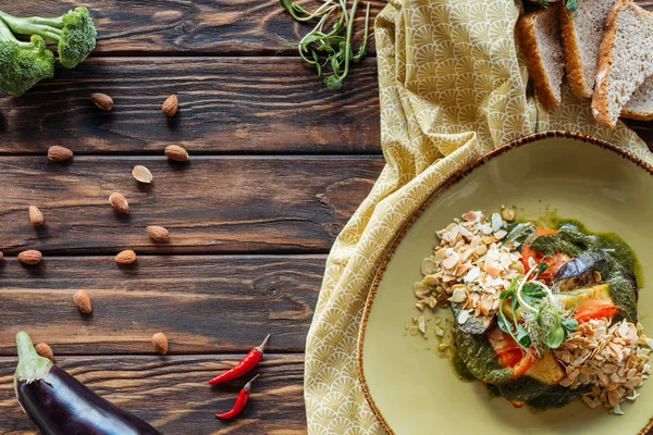 Flat lay with vegetarian salad, almonds, chili peppers and pieces of bread on wooden tabletop — Stock Photo