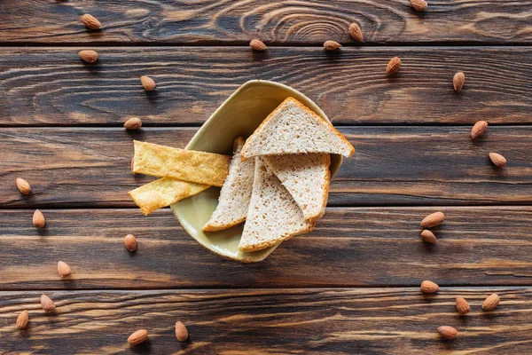 Вид зверху на мигдаль і миски з шматочками хліба на дерев'яній поверхні — стокове фото