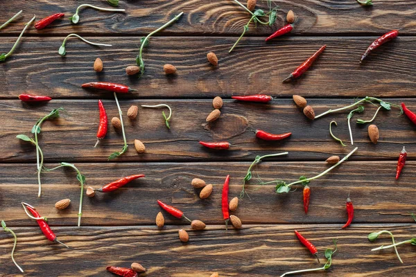 Marco completo de chiles arreglados, almendras y brotes en la mesa de madera - foto de stock