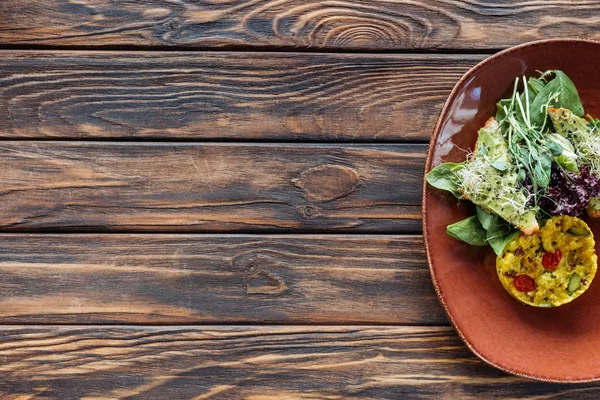 Vista dall'alto di insalata vegetariana con germogli e spinaci su piatto su superficie di legno — Foto stock