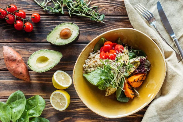 Flache Lage mit vegetarischem Salat mit gegrilltem Gemüse und Rosenkohl, Bettwäsche und Besteck auf Holzoberfläche — Stockfoto