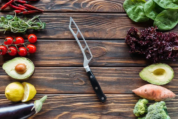 Vista superior de verduras frescas arregladas y cuchillo en la mesa de madera - foto de stock
