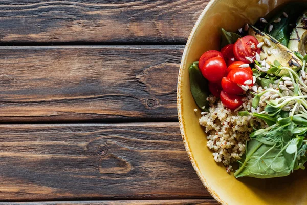 Вид зверху вегетаріанського салату з овочами на грилі, паростками, вишневими помідорами в мисці на дерев'яній стільниці — стокове фото