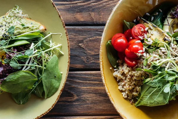 Flache Lage mit vegetarischen Salaten mit Spinat und Rosenkohl, serviert in Schüsseln auf hölzerner Tischplatte — Stockfoto