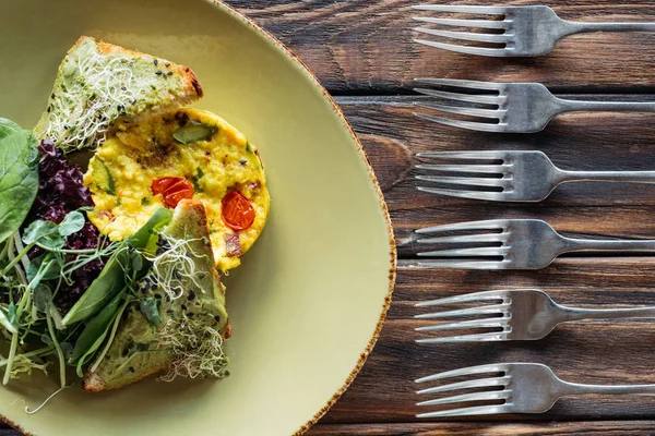 Vista dall'alto di insalata vegetariana e forchette disposte su superficie di legno — Foto stock