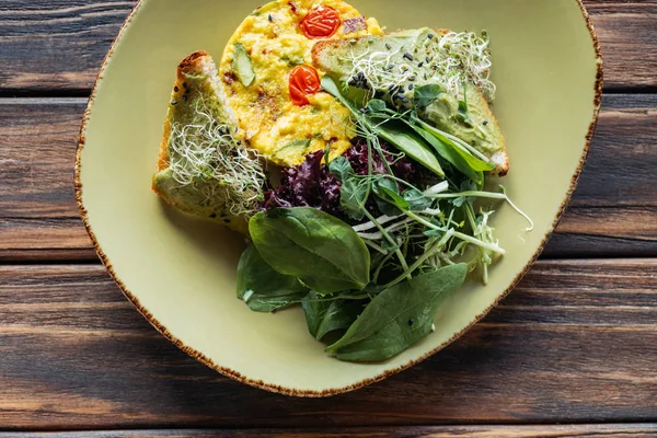 Top view of vegetarian salad with spinach and sprouts on plate on wooden tabletop — Stock Photo