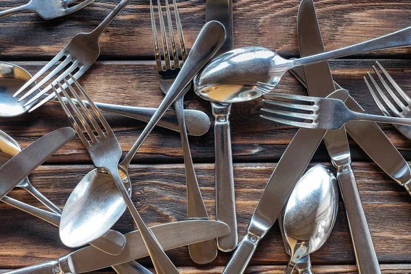 Cadre complet de couverts en acier disposés sur plateau en bois — Photo de stock