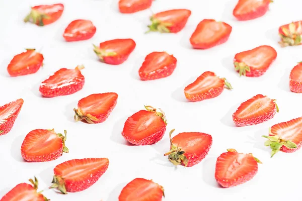 Frisch geschnittene Erdbeeren in Reihen auf weißem Hintergrund — Stockfoto