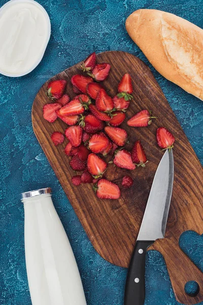 Schneiden von frischen Erdbeeren auf dem Tisch mit Brot und Milch — Stockfoto