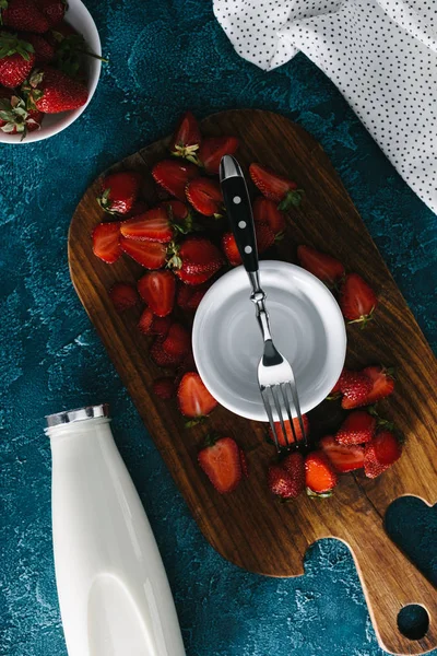 Top view of bowl with fork by ripe strawberries and milk bottle on table — Stock Photo