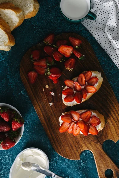 Top view of sandwiches with cream cheese and strawberries on wooden board — Stock Photo