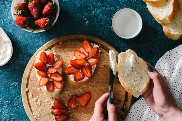 Frau bereitet Baguette mit Frischkäse und rohen Erdbeeren zu — Stockfoto