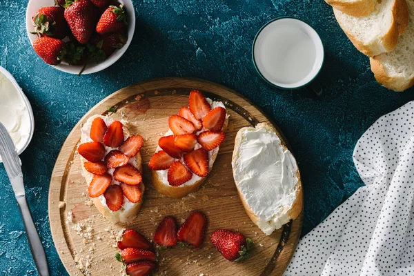 Vista superior de la comida de verano con queso crema y fresas en trozos de pan - foto de stock