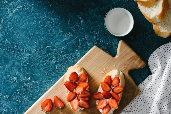 Placa de madeira com sanduíches de morango na mesa azul — Fotografia de Stock