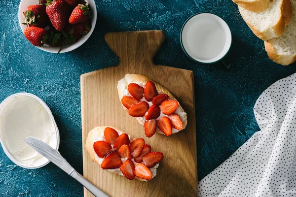 Vista superior do café da manhã de verão de pão branco com queijo creme e morangos em tábua de madeira — Fotografia de Stock