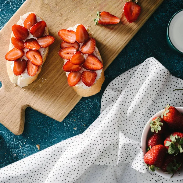 Raw strawberries and summer sandwiches with cream cheese on wooden board — Stock Photo