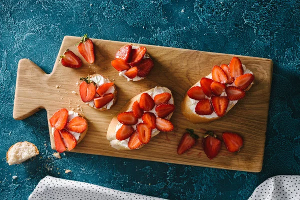 Baguete com creme de queijo e morangos de verão em tábua de madeira — Fotografia de Stock