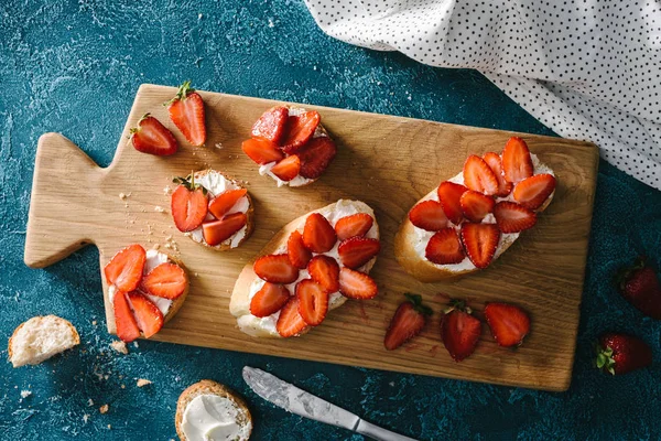 Frühstück mit Baguette mit Frischkäse und Erdbeeren auf Schneidebrett — Stockfoto