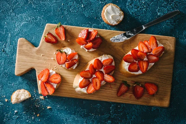 Cooking summer sandwiches with strawberries and soft cheese on wooden board — Stock Photo