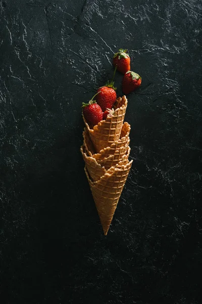 Morangos maduros em cones de waffle empilhados em fundo escuro — Fotografia de Stock