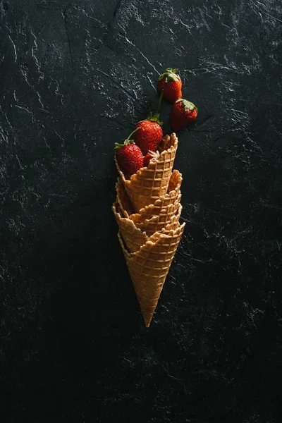 Ripe strawberries in stacked waffle cones on dark background — Stock Photo