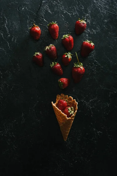 Vista superior de fresas rojas por cono de gofre sobre fondo oscuro - foto de stock