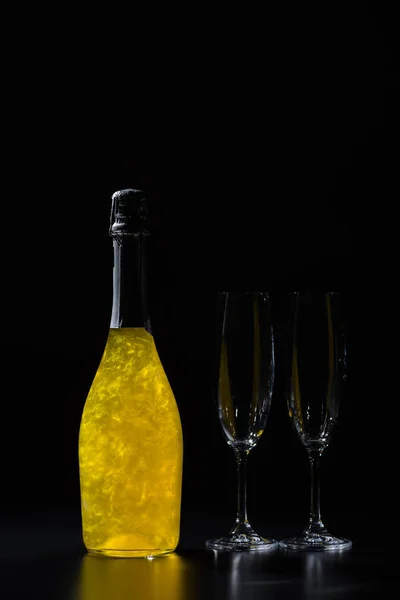 Vista da vicino di bottiglia di champagne e bicchieri vuoti su sfondo nero — Foto stock
