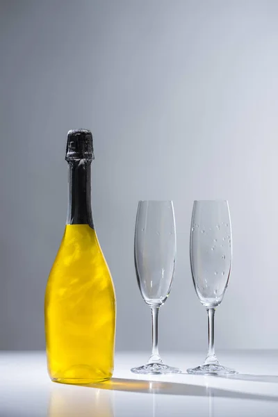Close up view of bottle of champagne and empty glasses on grey background — Stock Photo