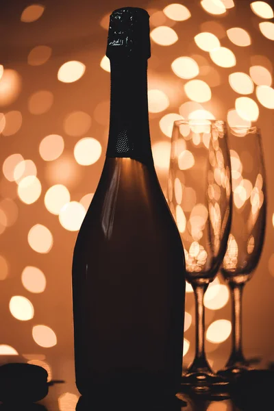 Vista de perto de garrafa de champanhe e copos vazios na mesa em estilo bokeh — Fotografia de Stock