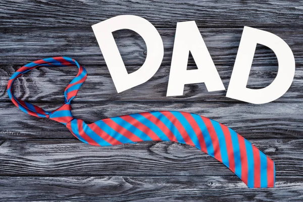 Вид зверху краватки з табличкою DAD на сірому дерев'яному стільниці, концепція Дня щасливих батьків — Stock Photo