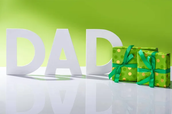 Cajas de regalo verdes frente a la inscripción de papá hechas de letras blancas en concepto de día de padres felices verde - foto de stock
