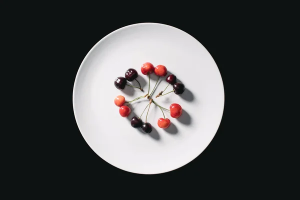 Top view of ripe red and yellow sweet cherries on round white plate isolated on black — Stock Photo