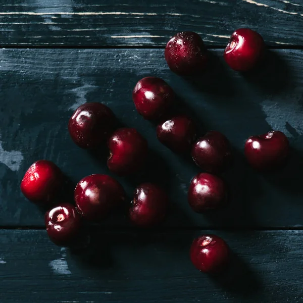 Vue de dessus des cerises mûres rouges sur la surface en bois humide — Photo de stock