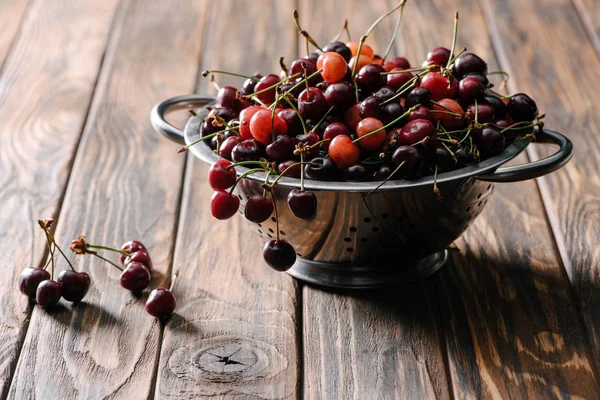 Colander with fresh sweet healthy cherries on rustic wooden table — Stock Photo