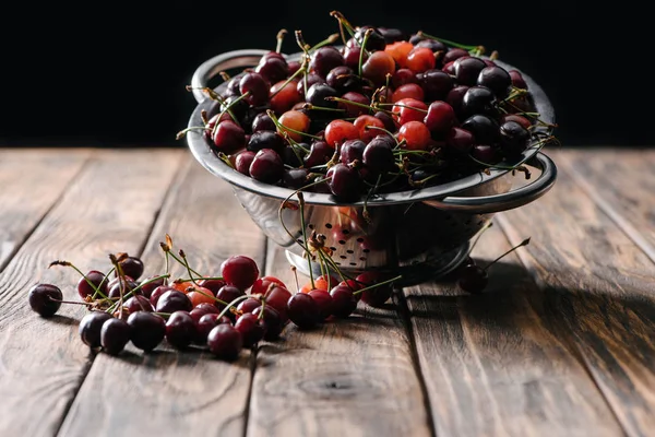 Cerises douces mûres fraîches en passoire sur table en bois — Photo de stock