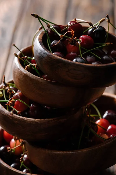 Vista de cerca de cuencos apilados con cerezas maduras frescas en la mesa de madera - foto de stock