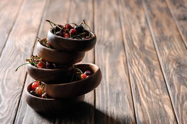 Tour faite de bols avec des cerises fraîches mûres sur une table en bois — Photo de stock
