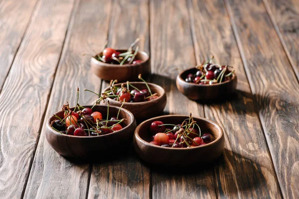 Cerezas dulces maduras frescas en cuencos sobre mesa de madera - foto de stock