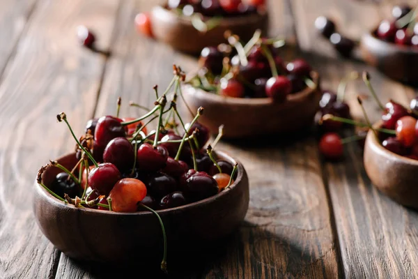 Vue rapprochée de cerises douces fraîches mûres dans des bols sur une table en bois — Photo de stock