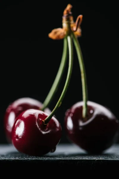 Vista de cerca de cerezas orgánicas maduras con gotas de agua en negro - foto de stock