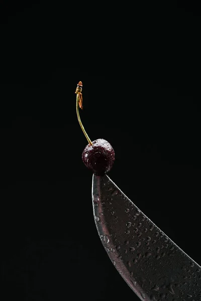 Close-up view of single ripe sweet cherry on knife isolated on black — Stock Photo