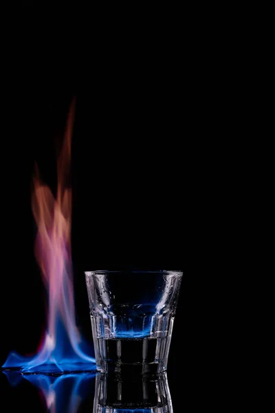 Закрыть вид на стекло горящего напитка самбука на черном фоне — стоковое фото