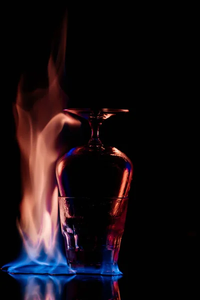 Крупним планом вид окулярів і спалювання спиртного напою Санбука навколо на чорному фоні — стокове фото