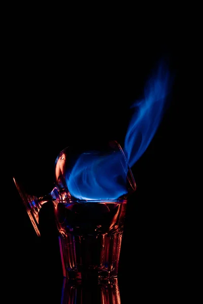 Primer plano vista de alcohol sambuca bebida quema en vidrio sobre fondo negro - foto de stock