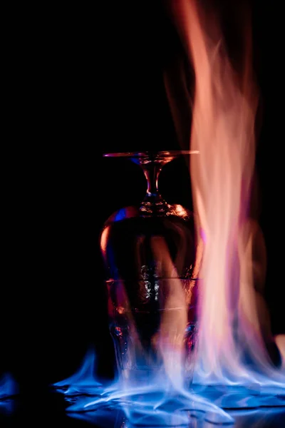Закрыть вид на алкогольный напиток самбука в стекле и пламя на черном фоне — стоковое фото